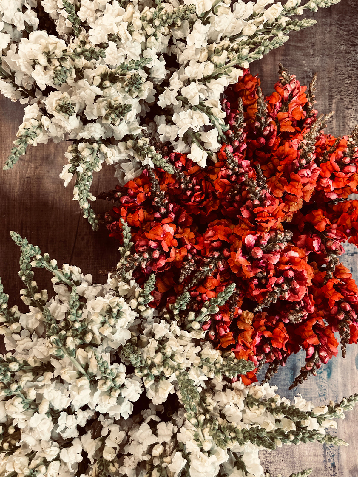 Bouquets of white and red flowers are arranged on a wooden surface.